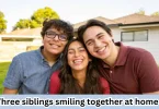Three siblings smiling together at home